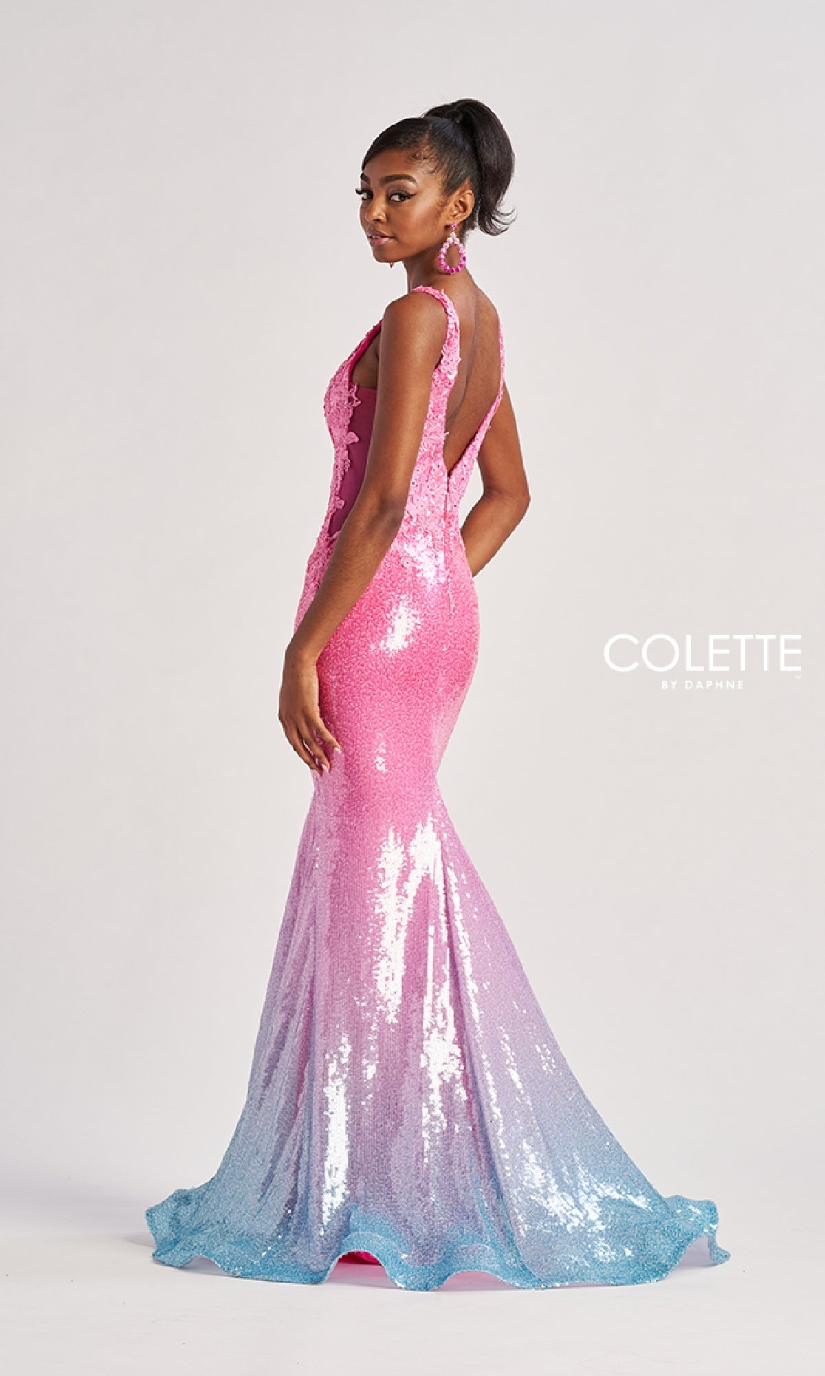 A woman poses against a plain white background wearing the Colette CL8605 long prom dress, a sleeveless, backless mermaid gown adorned with pink, purple, and blue sequins.